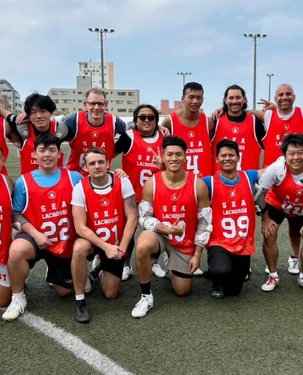 A group of players in red numbered bibs posing together outdoors